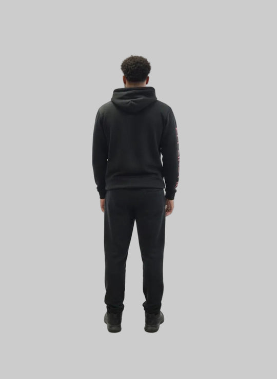 Person wearing a black hoodie and pants on a white background