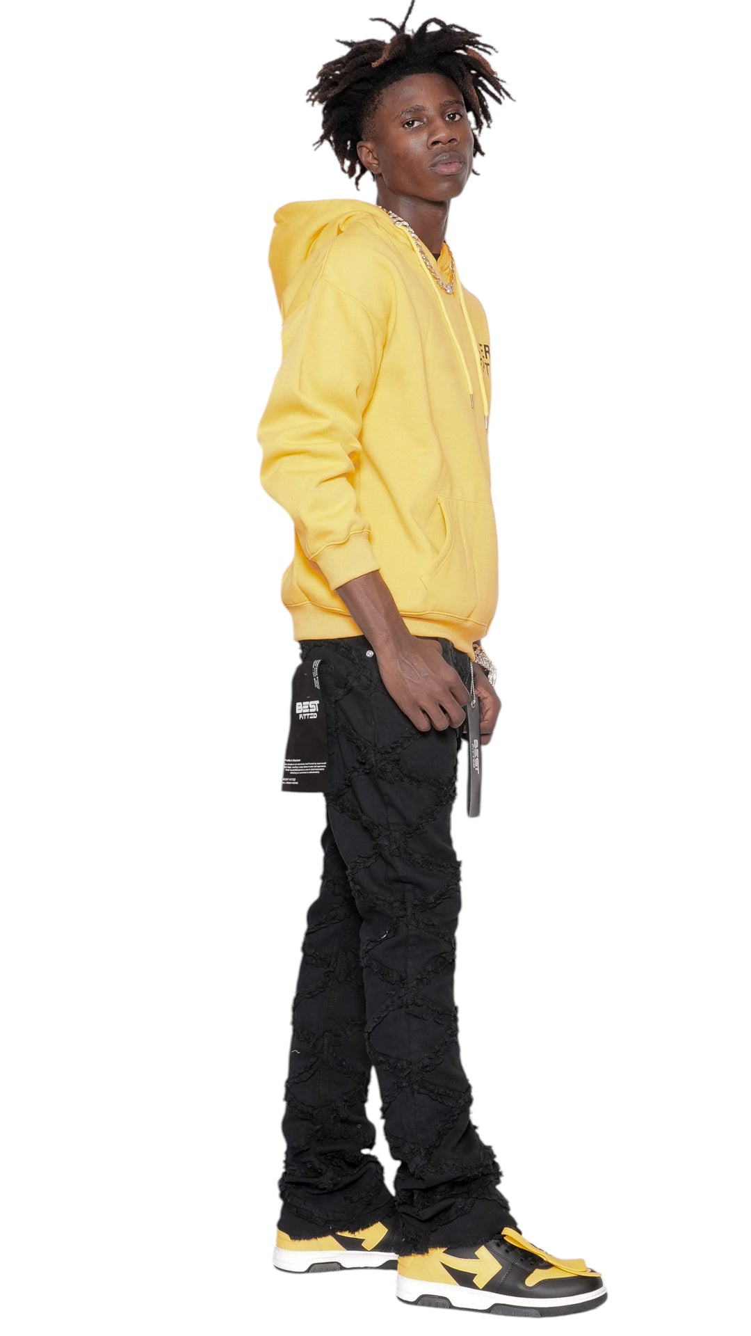 Person wearing a yellow hoodie and black pants on a white background