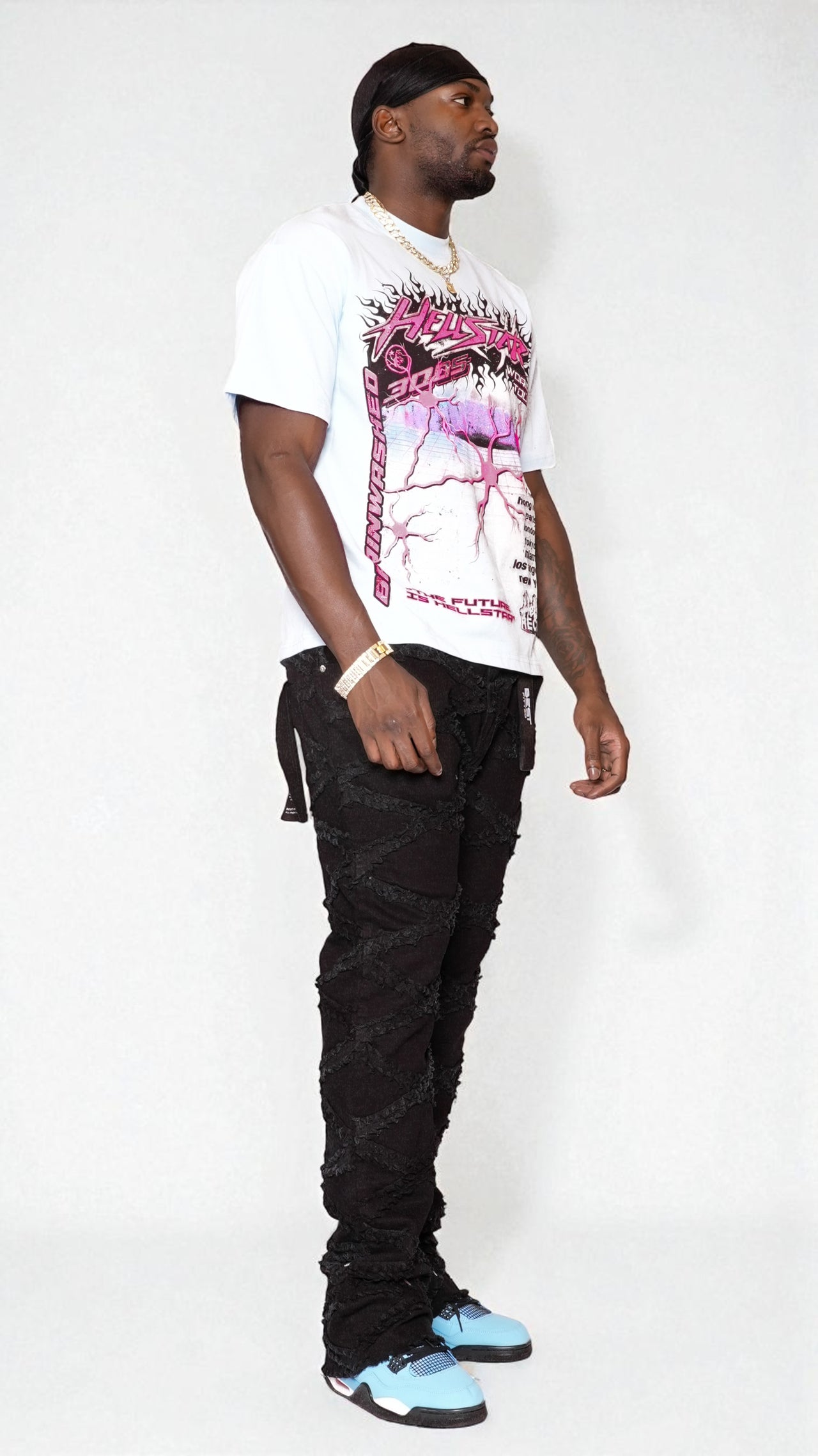 Man wearing a white graphic t-shirt, black pants, and light blue sneakers on a white background