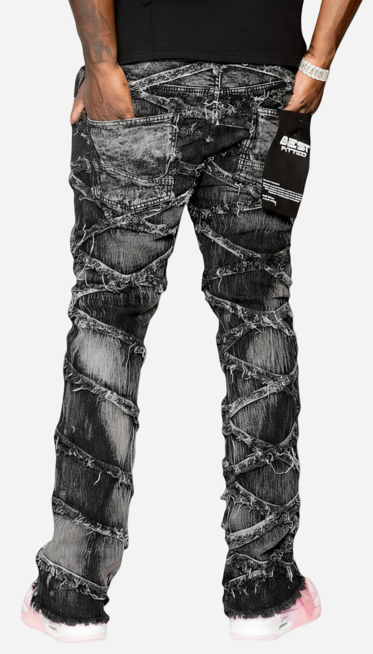 Distressed black jeans worn by a person on a gray background