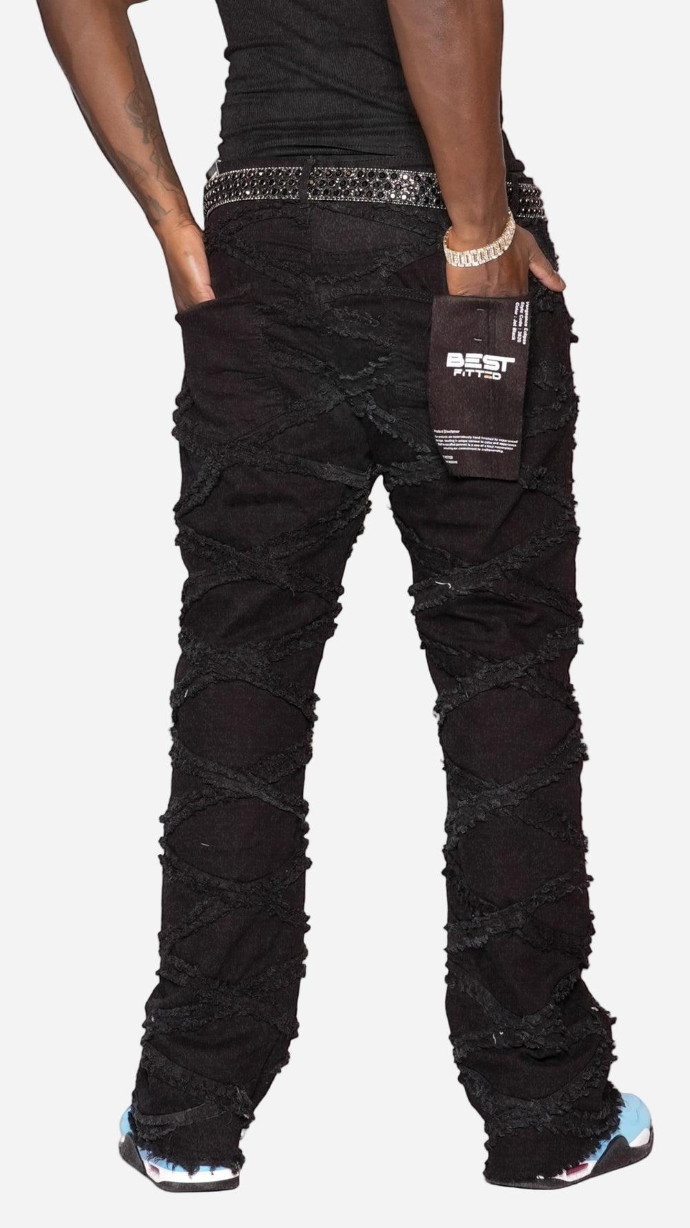 Black distressed jeans worn by a person on a white background