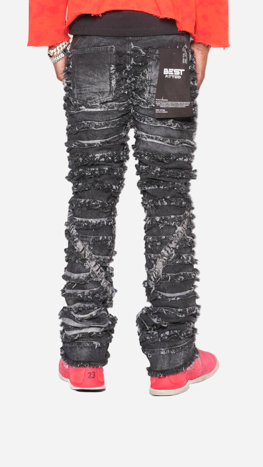 Person wearing black distressed jeans with a red jacket and pink shoes on a reflective surface.