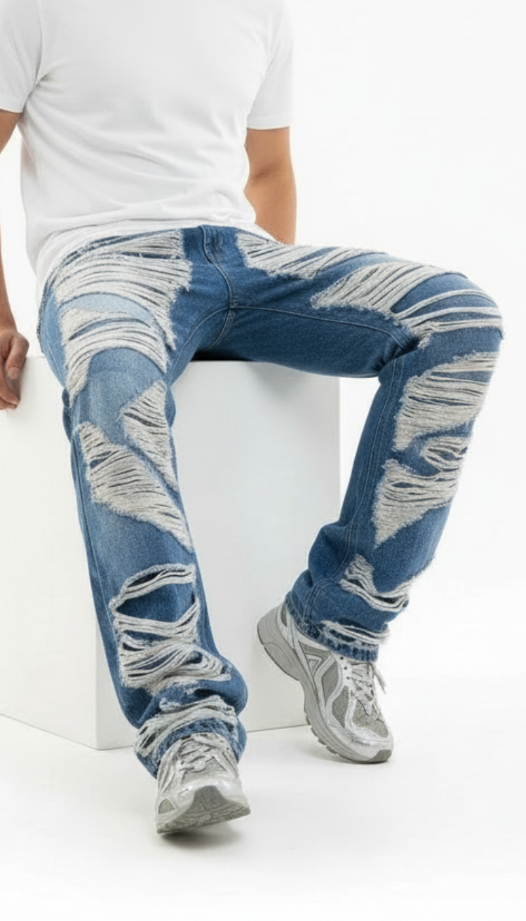 Person wearing blue distressed jeans and gray sneakers on a white background