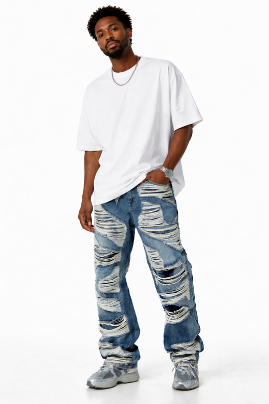 Man wearing a white oversized shirt and distressed blue jeans on a white background