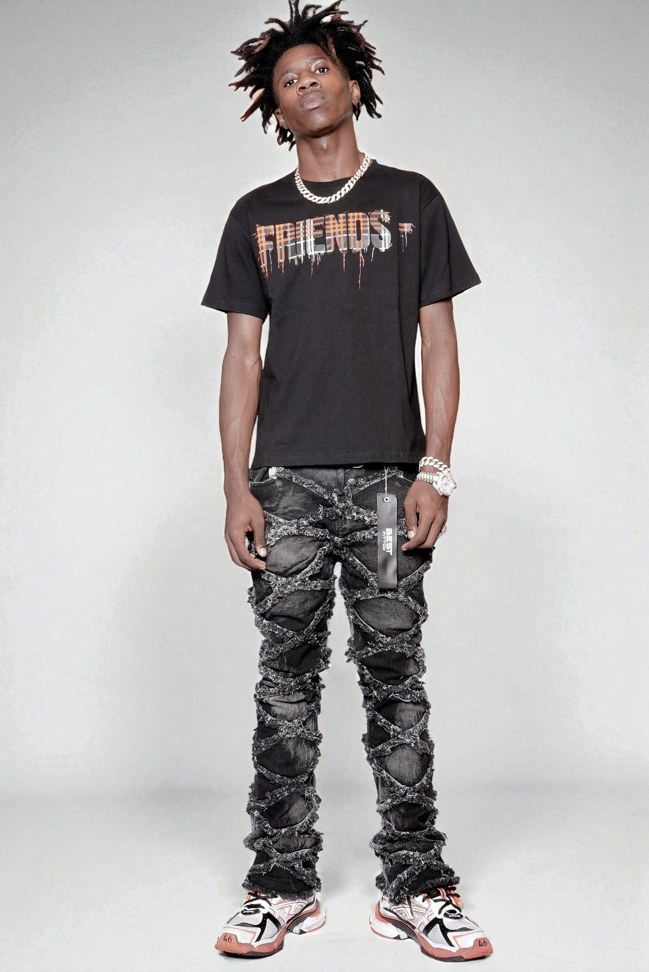 Person wearing a black 'Friends' t-shirt and ripped jeans on a white background