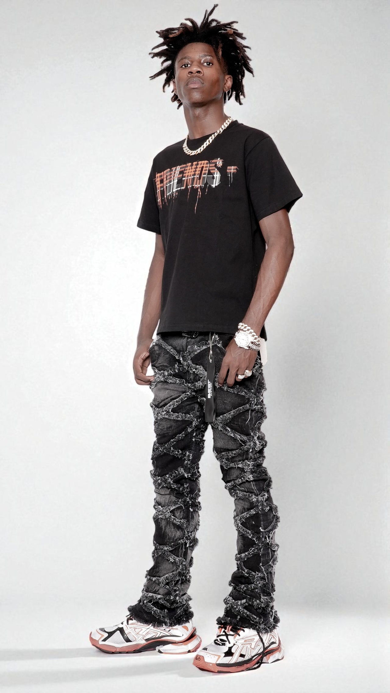 Person wearing a black t-shirt and patterned jeans on a white background