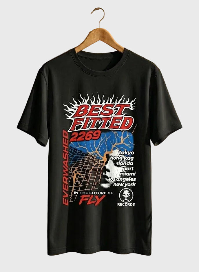 Black t-shirt with colorful graphics and text on a hanger against a beige wall.