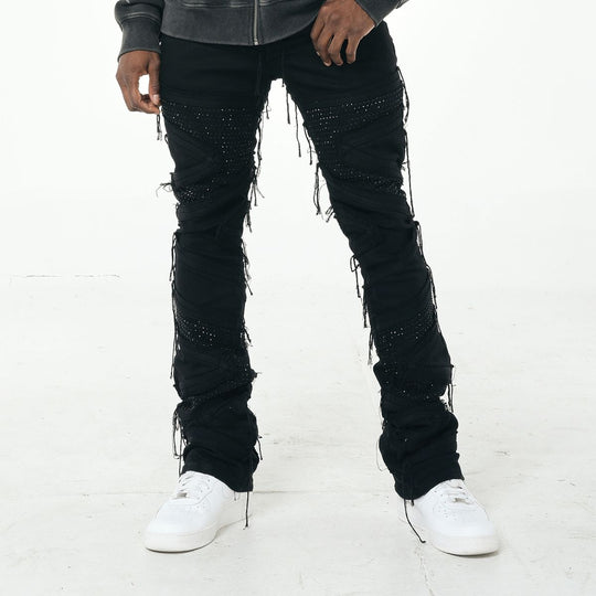Person wearing black embellished jeans with white sneakers on a white background