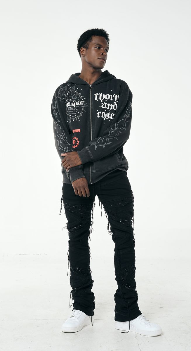 Person wearing a black hoodie with text and graphics, black pants, and white shoes on a white background