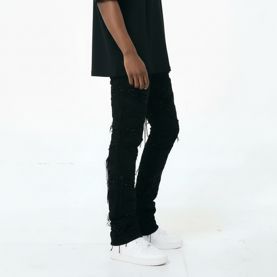 Person wearing black distressed jeans and white sneakers on a white background