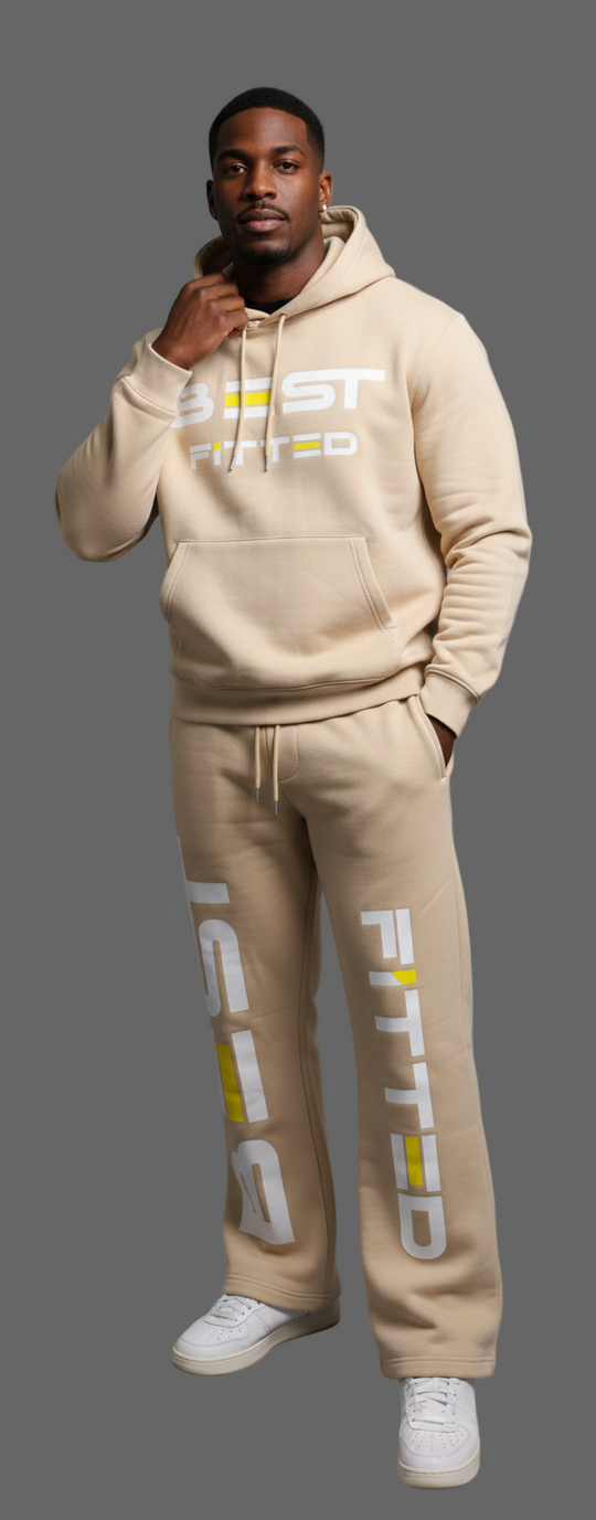 Man wearing a beige hoodie and pants with brand logos on a gray background