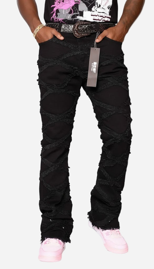 Person wearing black distressed jeans with a tag, standing against a white background