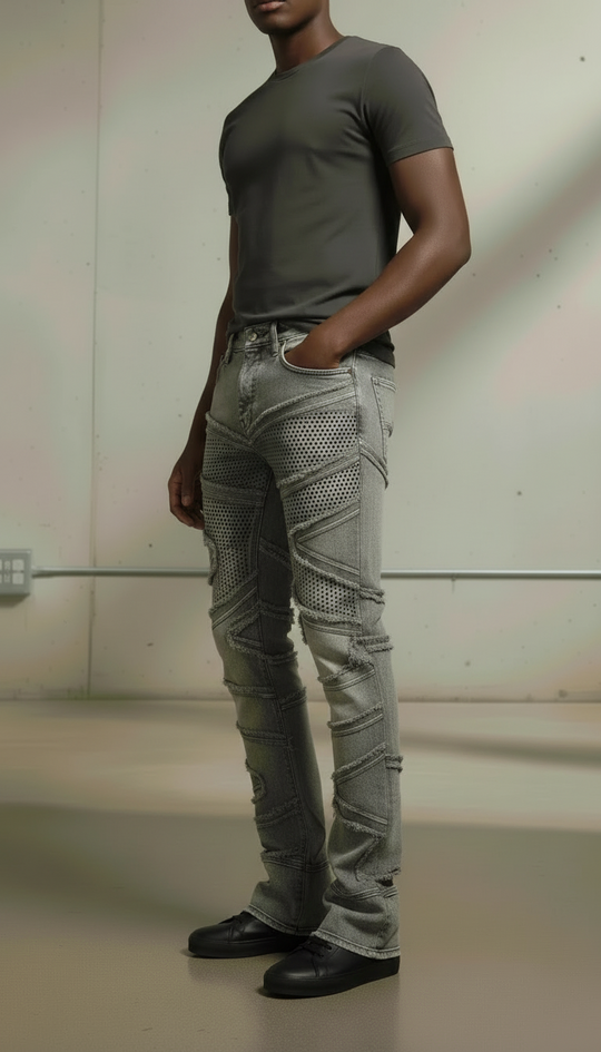 Person wearing a gray t-shirt and patterned gray jeans against a neutral background