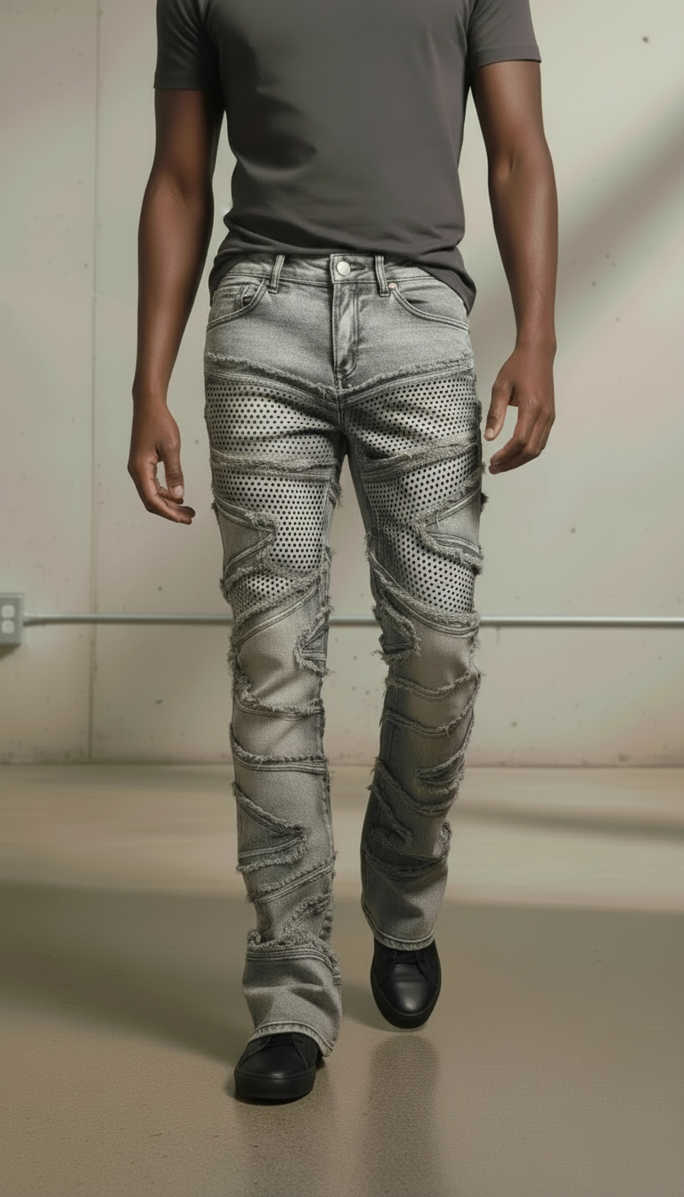 Person wearing a gray t-shirt and patterned gray jeans on a plain background