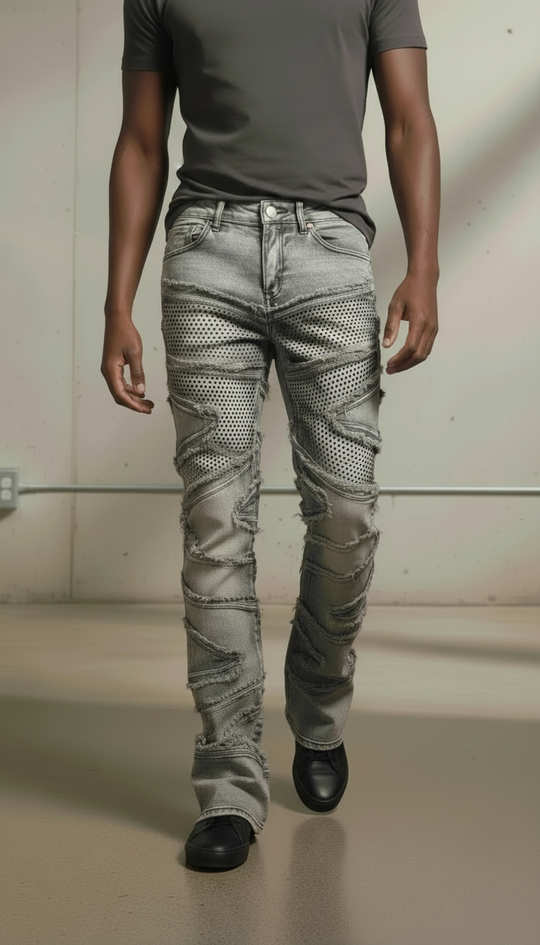 Person wearing a gray t-shirt and patterned gray jeans on a plain background