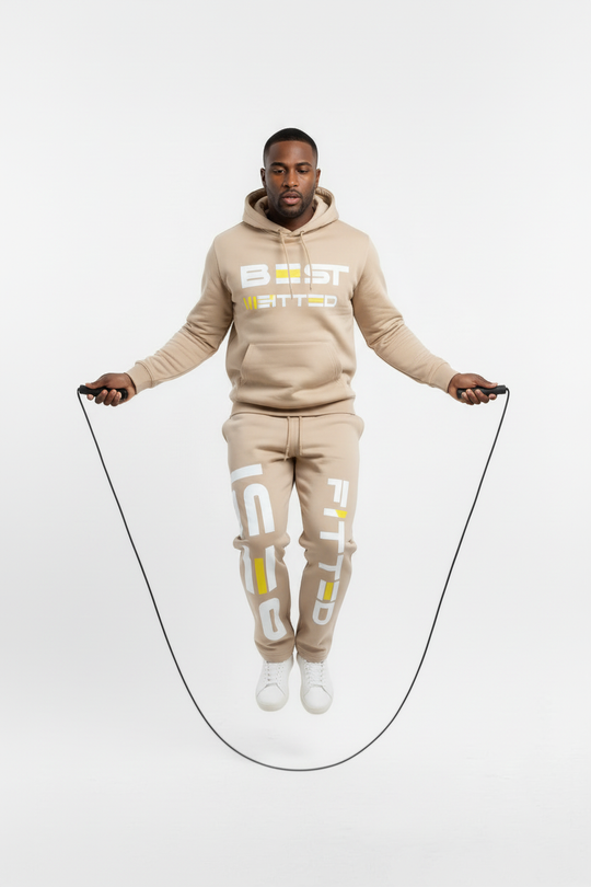 Man in a beige 'Beast Mode' tracksuit jumping rope on a white background