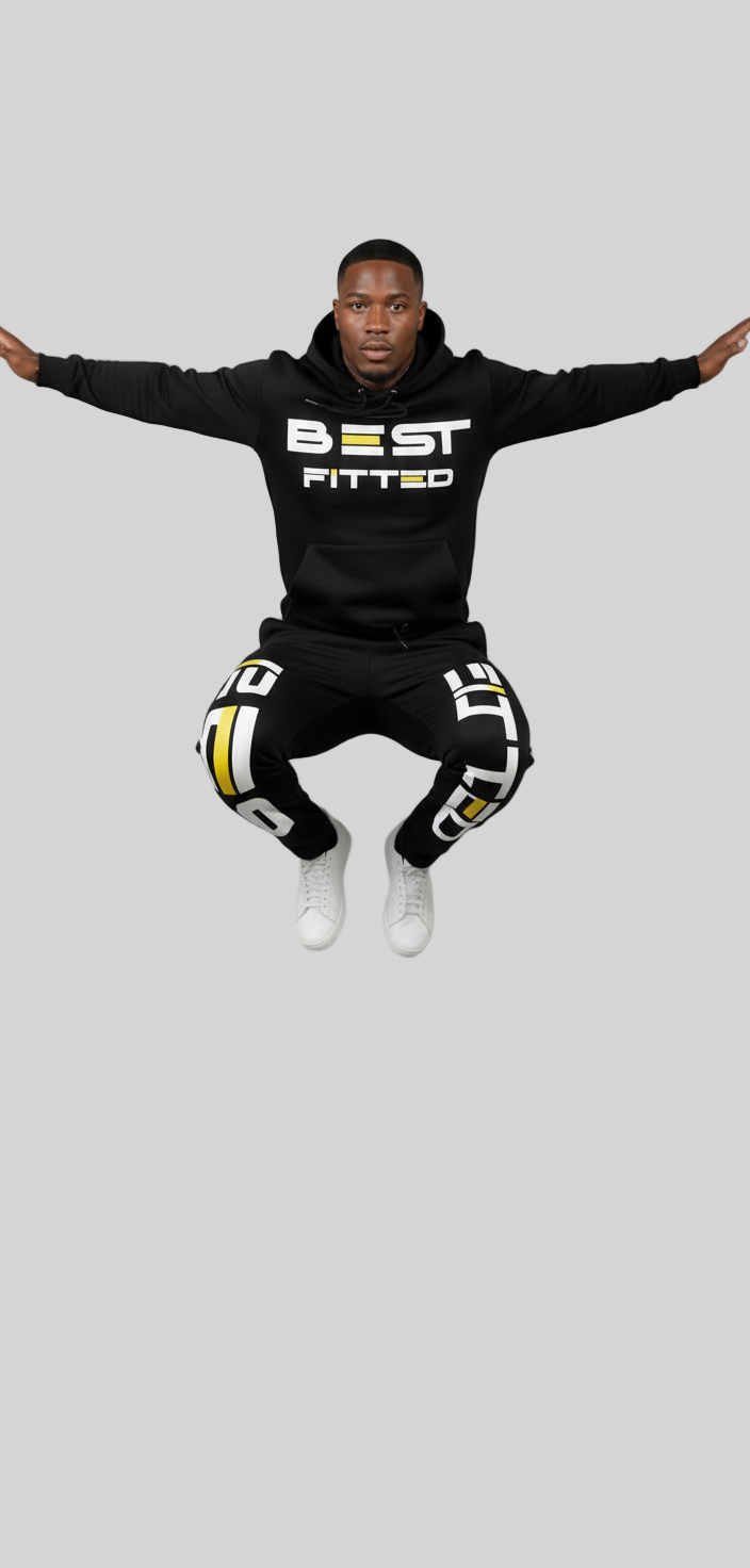 Person wearing a black hoodie with 'BEST FITTED' text, black pants with white patterns, and white shoes on a gray background.