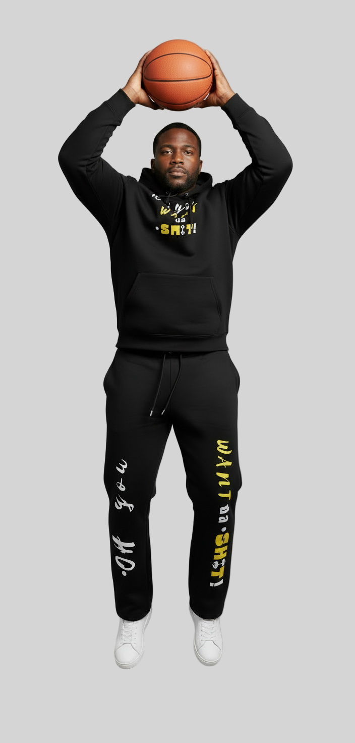 Person wearing a black hoodie and pants with text, holding a basketball against a gray background