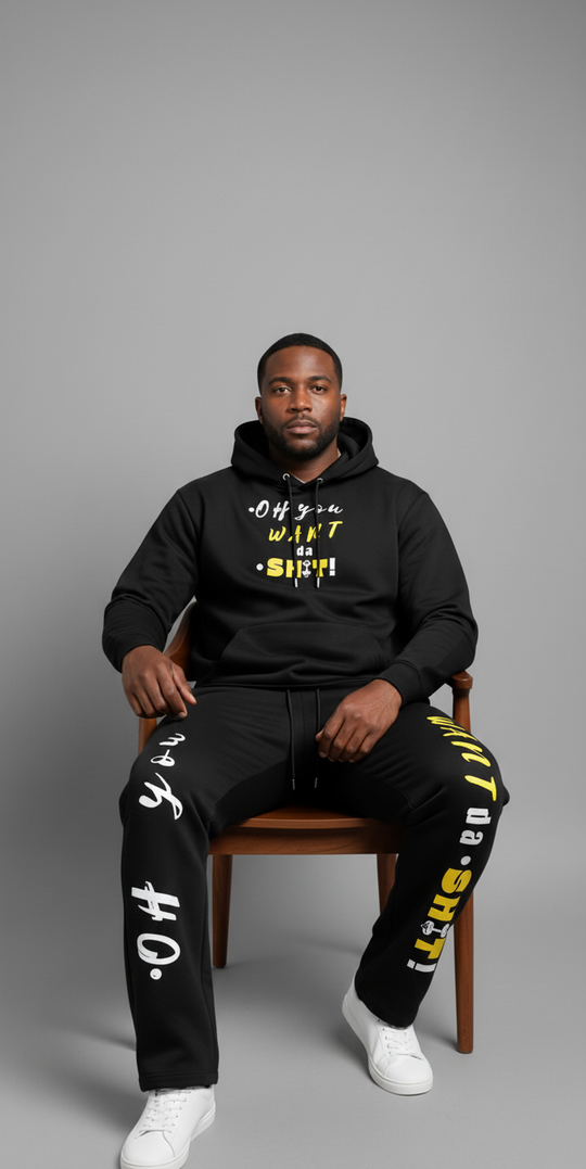 Man wearing a black hoodie and pants with text, sitting on a chair against a gray background