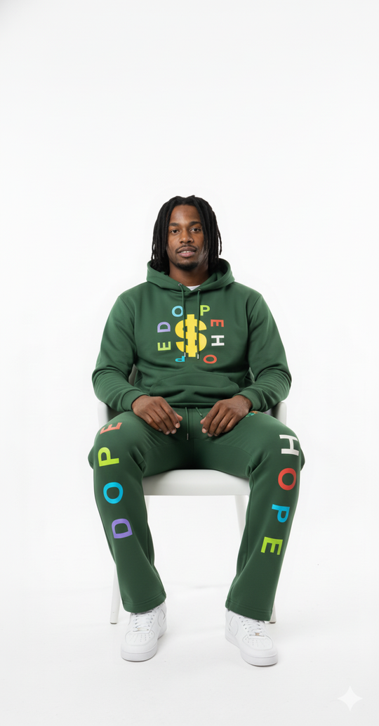 Person wearing a green hoodie and pants with colorful text sitting on a white chair against a white background